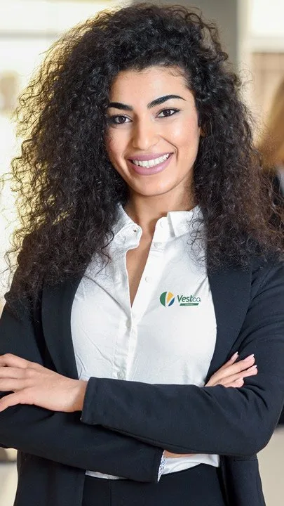 Executiva de blazer preto e camisa branca com logotipo VestCo bordado no peito
