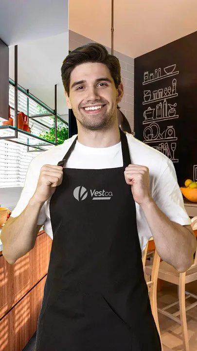 Cozinheiro sorrindo vestindo avental preto VestCo com logotipo bordado, em cozinha profissional